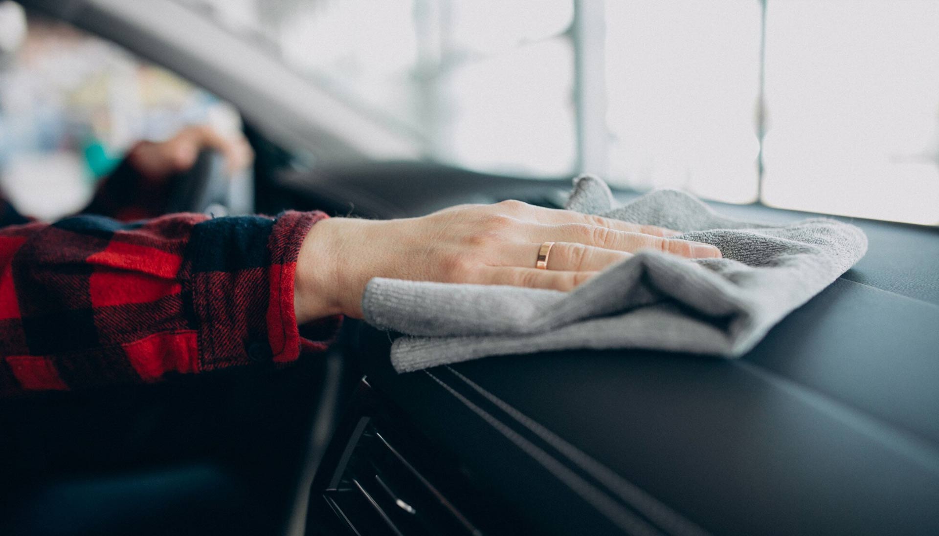 Someone detailing their car’s interior dashboard, carefully cleaning and polishing the surfaces to ensure a spotless finish.