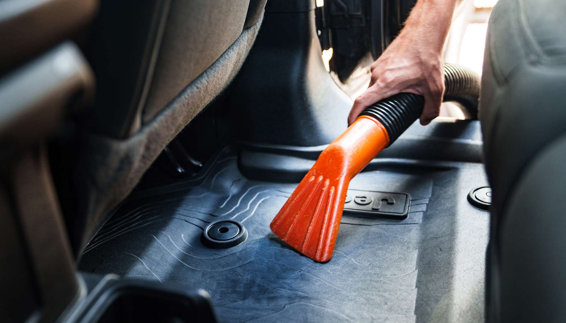 A person using a vacuum station to clean the interior of their car, focusing on detailed cleaning of the seats and floor mats.